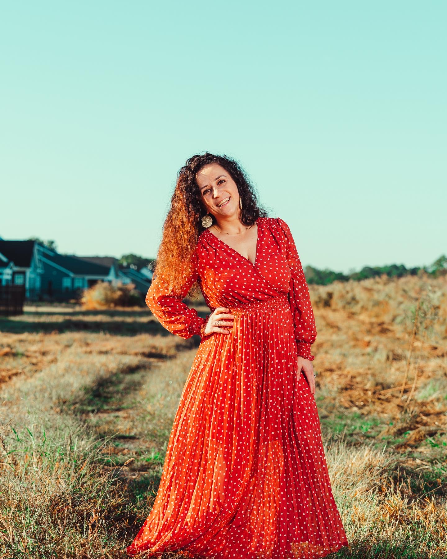 Fate Winczuk in a red dress in a sunlit field